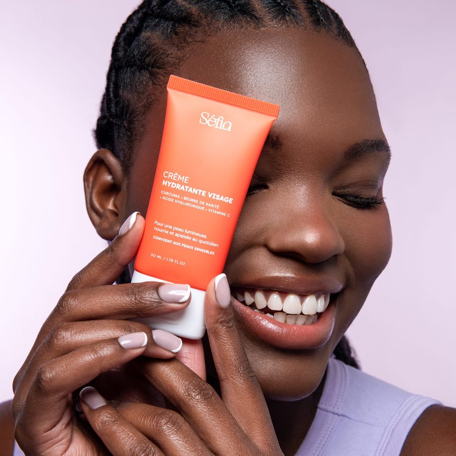 Une cliente sourit, la Crème Hydratante Visage Séfia à la main